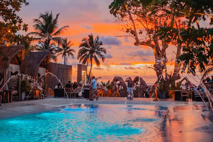 Atardecer en Vistamar Beach Club en Coveñas, con piscina iluminada, palmeras y ambiente tropical frente al mar.